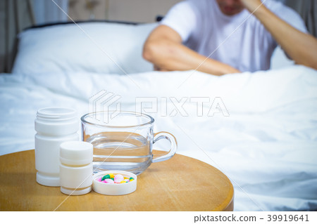 man on bed with medicine, drugs and glass of water man on bed with medicine, drugs and glass of water 39919641