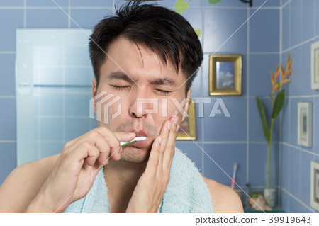 asian man with toothache while brushing teeth asian man with toothache while brushing teeth 39919643