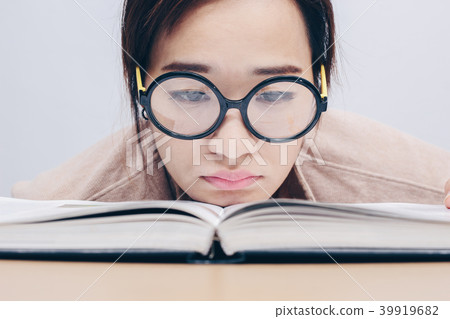 Nerdy female student bored with reading book Nerdy female student bored with reading book 39919682