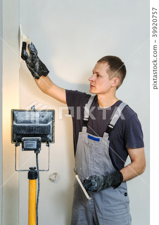 Worker makes final smoothing plaster on the wall. Worker makes final smoothing plaster on the wall. 39920757
