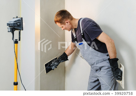 Worker makes final smoothing plaster on the wall. 39920758
