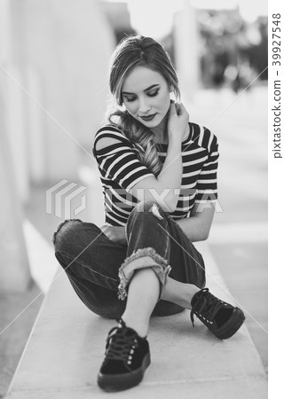 Blonde woman, model of fashion, sitting in urban background. Blonde woman, model of fashion, sitting in urban background. 39927548