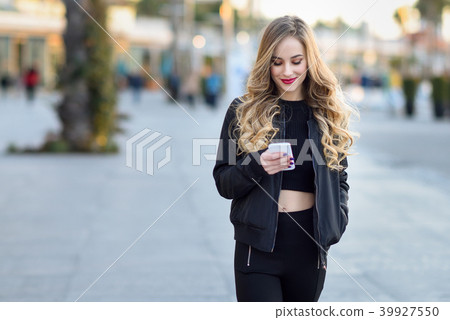 Blonde woman texting with her smartphone in urban background 39927550