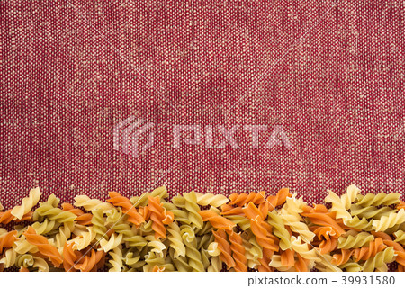 Multicolor spiral macaroni Beautiful decomposed pasta from the bottom on a rustic red-brown textured Multicolor spiral macaroni Beautiful decomposed pasta from the bottom on a rustic red-brown textured 39931580