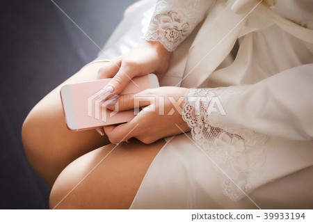 Hands close up of a bride in a peignoir holding phone Hands close up of a bride in a peignoir holding phone 39933194