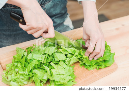 Close-up Female hands chopping a green plant salad cooking salad from vegetables on a wooden cutting Close-up Female hands chopping a green plant salad cooking salad from vegetables on a wooden cutting 39934377