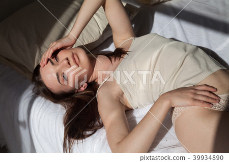 brunette in lingerie lay on a white bed in the bedroom brunette in lingerie lay on a white bed in the bedroom 39934890