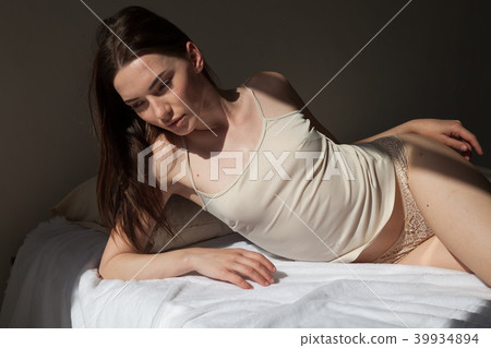 brunette in lingerie lay on a white bed in the bedroom brunette in lingerie lay on a white bed in the bedroom 39934894
