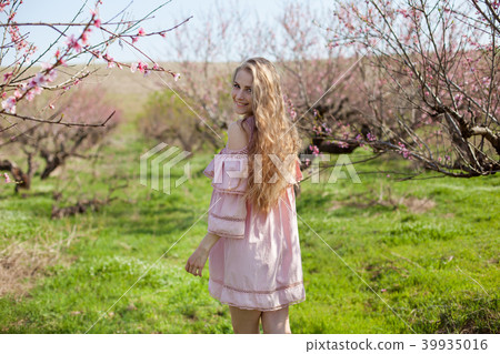 blonde in pink dress walks in the garden with flowering trees 39935016