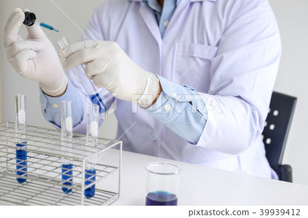 Scientist or medical in lab coat holding test tube with reagent 39939412