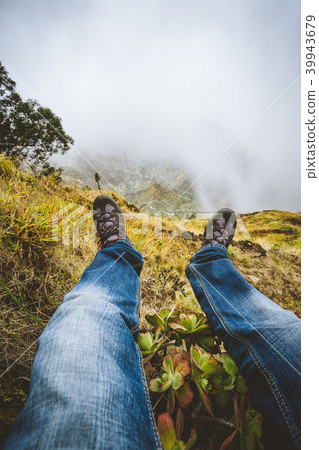Traveler hiking boots over impressive verdant Xo-Xo valley with mountain peaks, rugged cliffs in fog Traveler hiking boots over impressive verdant Xo-Xo valley with mountain peaks, rugged cliffs in fog 39943679