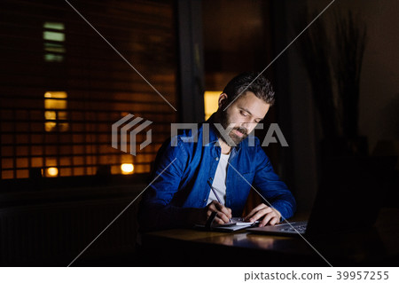 A man working on a laptop at home at night. A man working on a laptop at home at night. 39957255