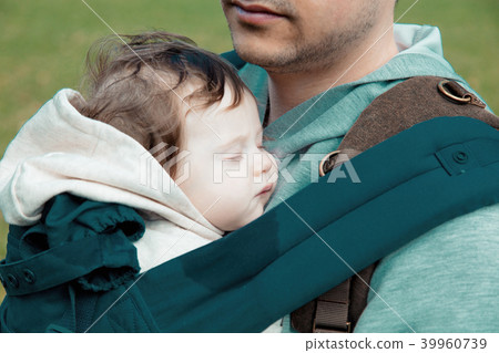 father holding a little child in a backpack 39960739