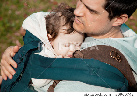 father holding a little child in a backpack 39960742