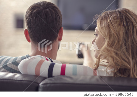 Happy young couple relaxing and watching TV at home. Happy young couple relaxing and watching TV at home. 39965545