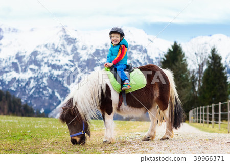 Kids riding pony. Child on horse in Alps mountains Kids riding pony. Child on horse in Alps mountains 39966371