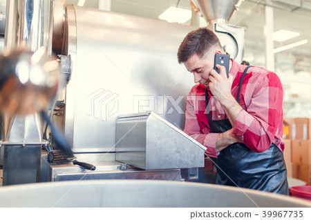 Image of businessman talking on phone at computer of industrial machine Image of businessman talking on phone at computer of industrial machine 39967735