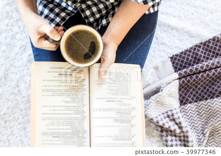 Woman with cup of coffee reading a book 39977346