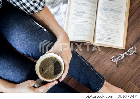 Woman with cup of coffee reading a book Woman with cup of coffee reading a book 39977347
