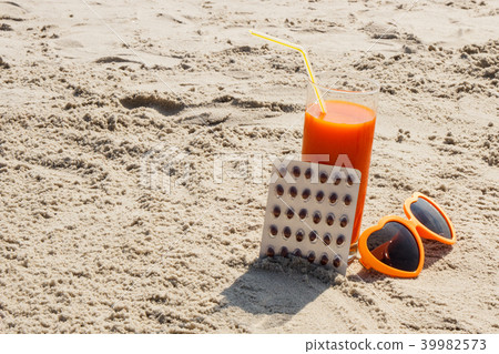 Medical pills, carrot juice and sunglasses on sand Medical pills, carrot juice and sunglasses on sand 39982573