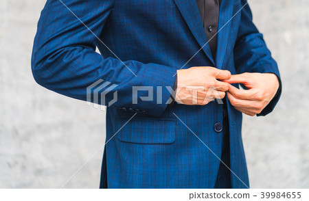Man wear suit fixing button in front of the wall Man wear suit fixing button in front of the wall 39984655