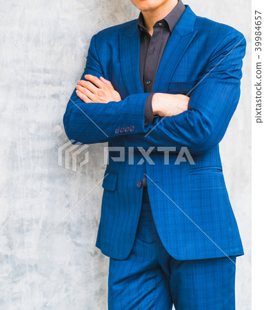 A man wearing a suit in front of a wall. A man wearing a suit in front of a wall. 39984657