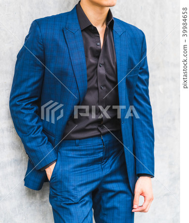 A man wearing a suit in front of a wall. A man wearing a suit in front of a wall. 39984658