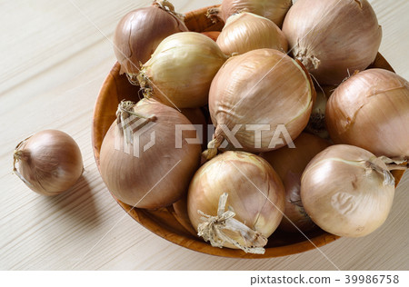 Bulbs in a bowl and one onion on a wooden table Bulbs in a bowl and one onion on a wooden table 39986758