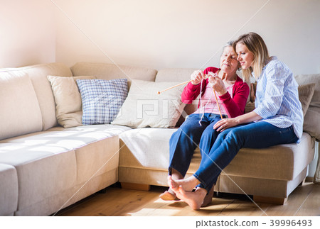 Elderly grandmother and adult granddaughter at home, knitting. 39996493