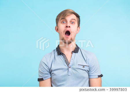 Closeup portrait of shocked stunned surprised young man eyes and mouth wide open on blue background 39997803