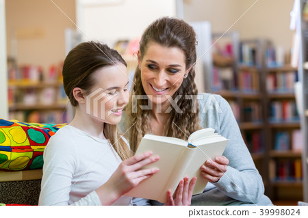 Mother and daughter reading a book in community center library Mother and daughter reading a book in community center library 39998024