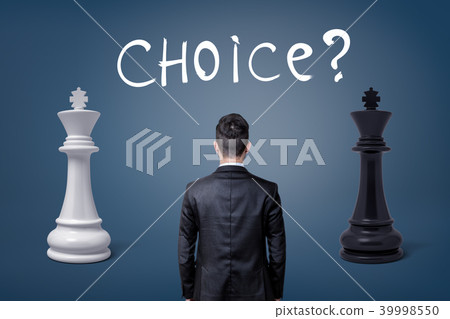 A view on a businessman's back as he stands between two chess kings and a lettering Choice. 39998550