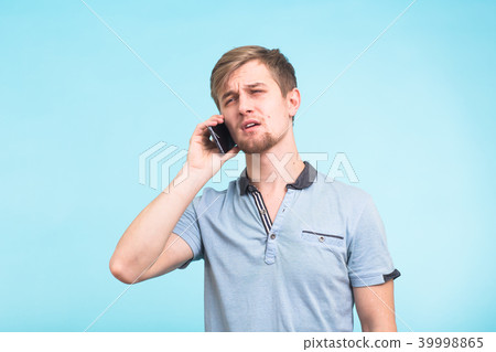 Portrait of young man talking on phone over blue background 39998865