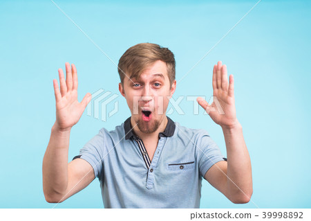 Young hipster man with holding something very big, size concept over blue background 39998892