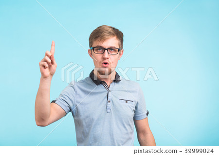 Wow, I understand it. Surprised young male raises finger as remembers something, isolated over blue 39999024