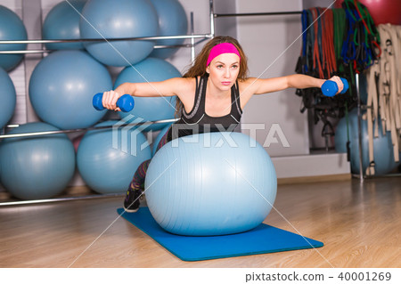 Woman exercising with dumbbells on a fitness ball Woman exercising with dumbbells on a fitness ball 40001269