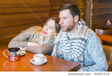 Happy young couple is drinking coffee and smiling while sitting at the cafe. Happy young couple is drinking coffee and smiling while sitting at the cafe. 40001318