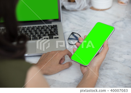 Close up woman hands using smartphone and laptop 40007083