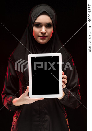 Portrait of beautiful smart young muslim woman wearing black hijab holding tablet in her hands as 40014877
