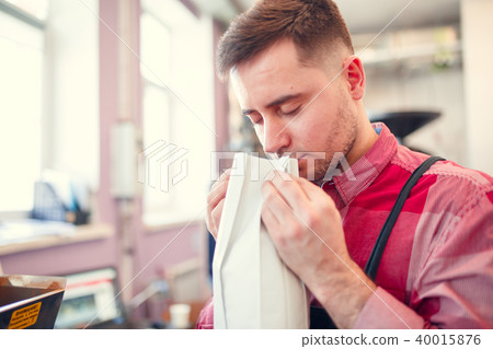 Photo of man sniffing coffee in paper bag 40015876
