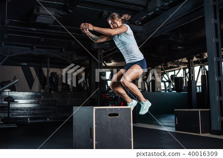 Sporty girl jumping over some boxes in gym 40016309