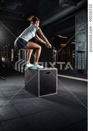 Sporty girl jumping over some boxes in gym 40016310