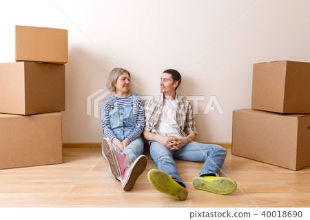 Photo of young married couple sitting on floor among cardboard boxes Photo of young married couple sitting on floor among cardboard boxes 40018690