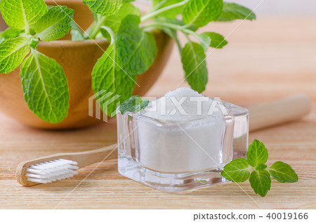 alternative natural toothpaste xylitol, soda, salt, and wood toothbrush closeup, mint on wooden 40019166