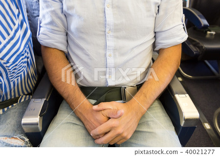 Male passenger with seat belt fastened while sitting on airplane for safe flight. Male passenger with seat belt fastened while sitting on airplane for safe flight. 40021277