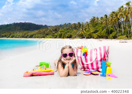 Child at tropical beach with bag and toys. 40022348