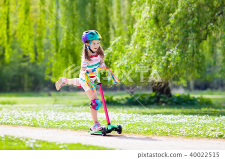 Child riding kick scooter in summer park. Child riding kick scooter in summer park. 40022515