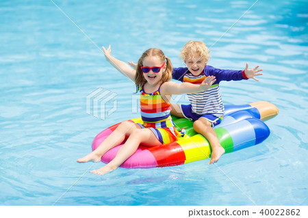 Kids on inflatable float in swimming pool. 40022862