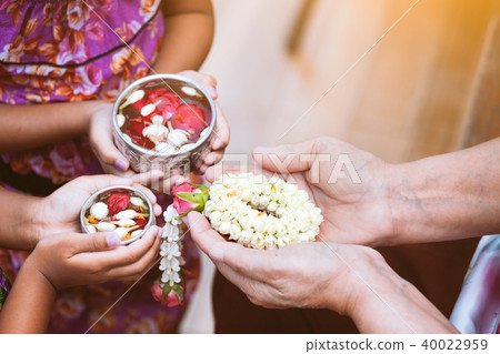child girl pouring water on hands of elder senior 40022959