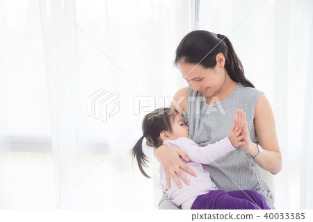 Pregnant mother breast feeding her daughter  40033385